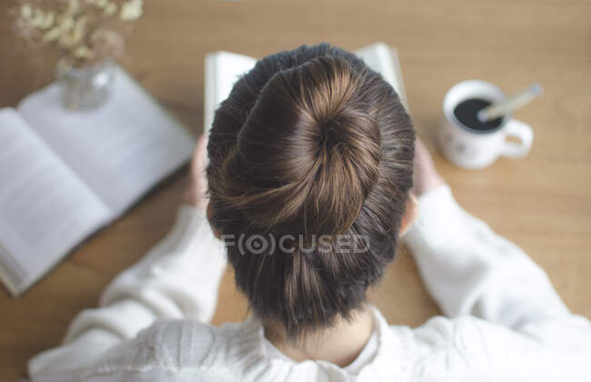 Вид сверху на девочку-подростка, читающую книгу — стоковое фото