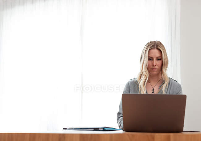 Femme assise dans un bureau travaillant sur un ordinateur portable — Photo de stock