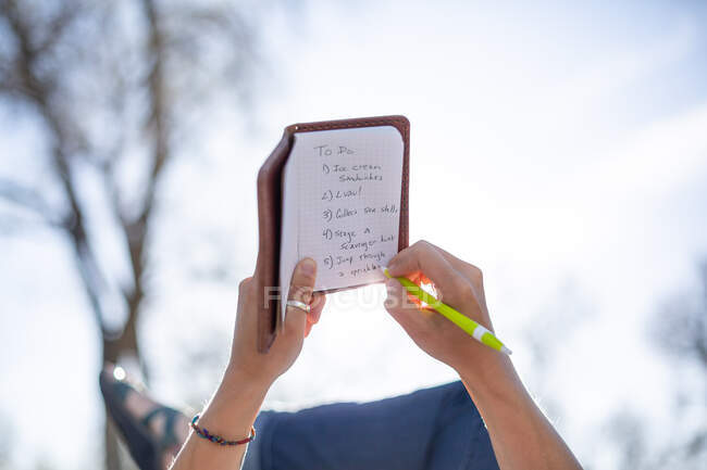Donna che scrive una lista delle cose da fare mentre si sdraia in giardino — Foto stock