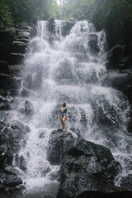 Donna in piedi sulle rocce vicino a una cascata, Bali, Indonesia — Foto stock