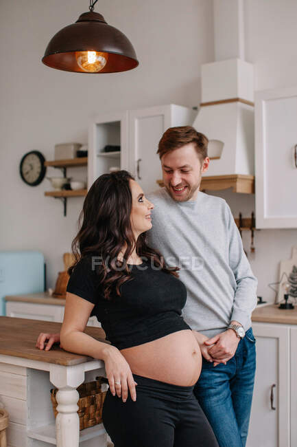 Беременная женщина, стоящая на кухне со своим мужем — стоковое фото
