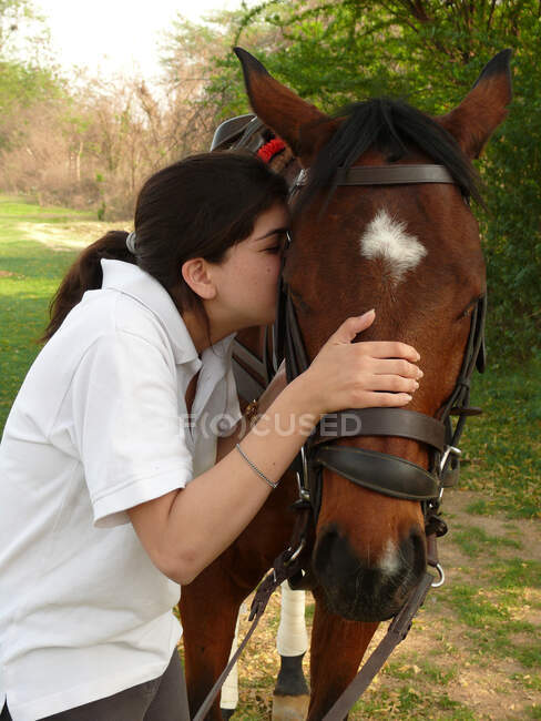 Jeune femme embrassant cheval brun — Photo de stock