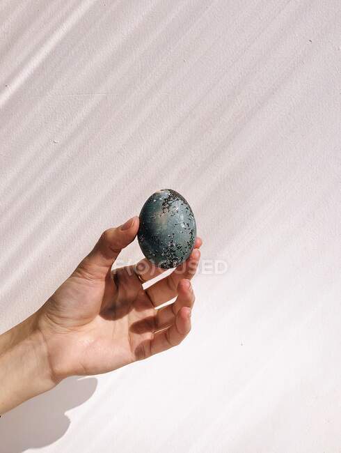 Uovo di Pasqua in mano su sfondo bianco — Foto stock