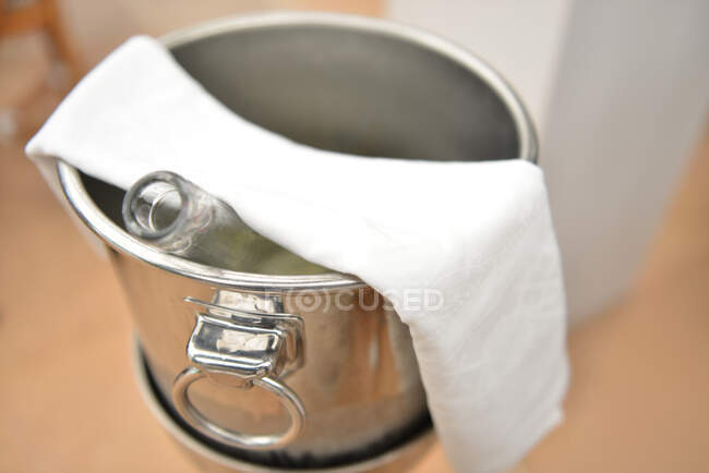 Tiro close-up de balde de metal com garrafa com toalha — Fotografia de Stock