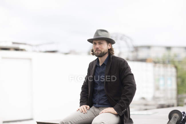 Портрет мужчины, сидящего на улице на стене — стоковое фото