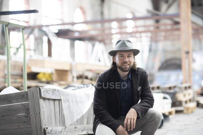 Retrato de um homem sorridente sentado num edifício a ser renovado — Fotografia de Stock