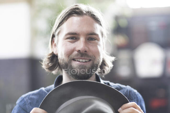 Portrait of a man holding  a hat in front of his face — Stock Photo