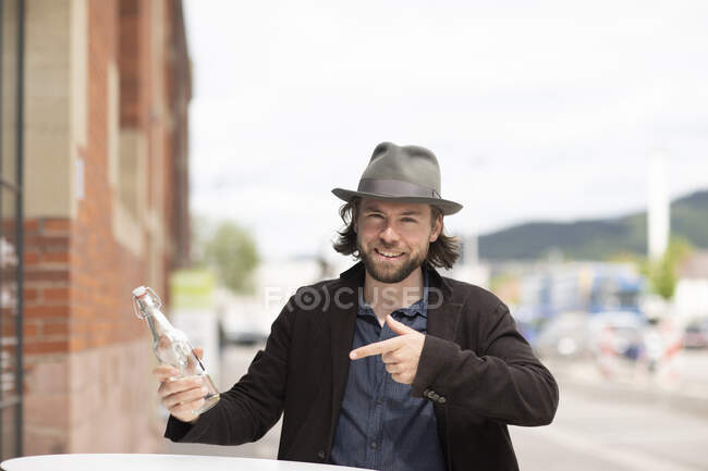 Retrato de un hombre sonriente apuntando a una botella de agua - foto de stock