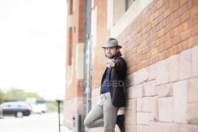 Retrato de un hombre apoyado contra una pared apuntando - foto de stock