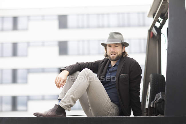 Portrait of a smiling man sitting on the back of a truck — Stock Photo