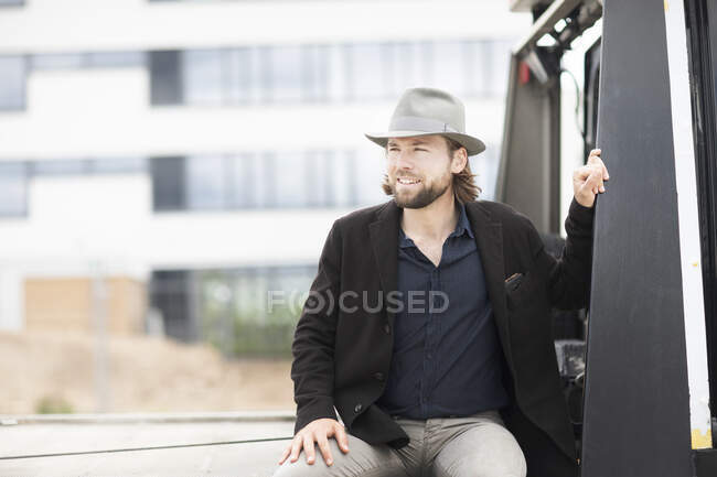 Retrato de un hombre sonriente sentado en la parte trasera de un camión - foto de stock