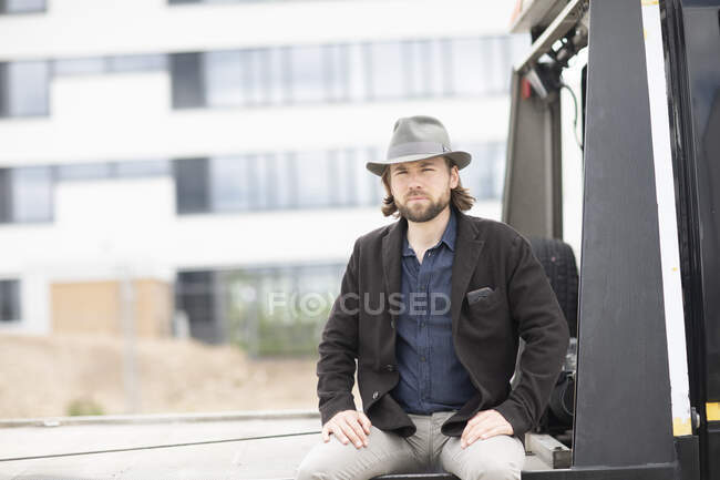 Retrato de un hombre sentado en la parte trasera de un camión - foto de stock