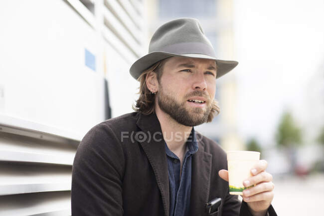 Portrait d'un homme assis à l'extérieur tenant une tasse de café — Photo de stock