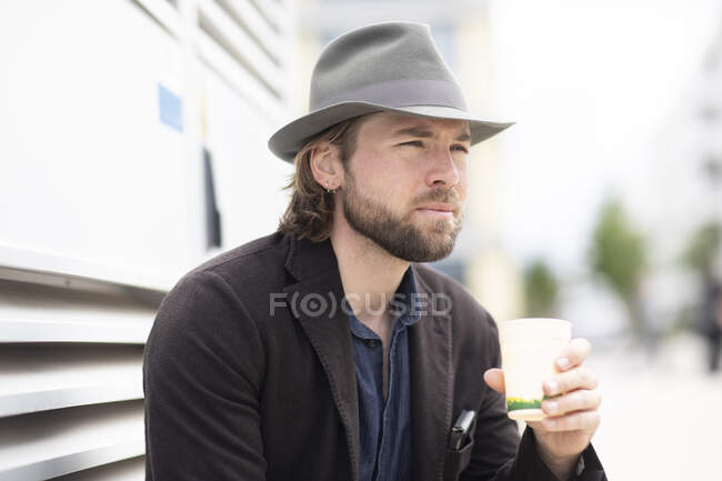 Портрет мужчины, сидящего на улице и держащего чашку кофе — стоковое фото