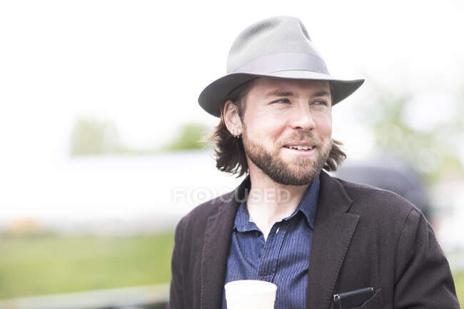 Portrait of a smiling man standing outdoors holding a cup of coffee — Stock Photo