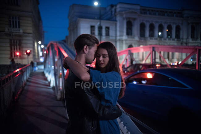 Пара стоїть на мосту вночі, обіймаючи Боснію і Герцеговину. — стокове фото