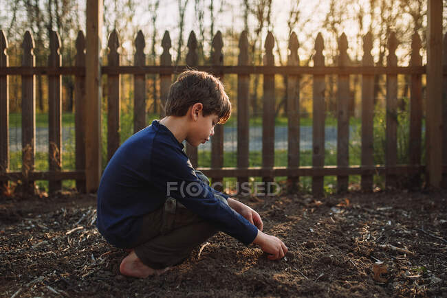 Descalzo sentado y tocando tierra al aire libre en el patio trasero - foto de stock