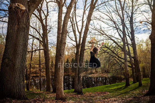Девушка качается на веревке качели в саду, США — стоковое фото