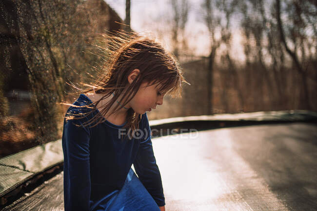 Chica sentada en un trampolín, Estados Unidos - foto de stock