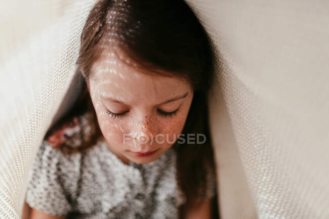 Ritratto di ragazza con lentiggini ricoperte di tessuto e raggi di sole sul viso — Foto stock