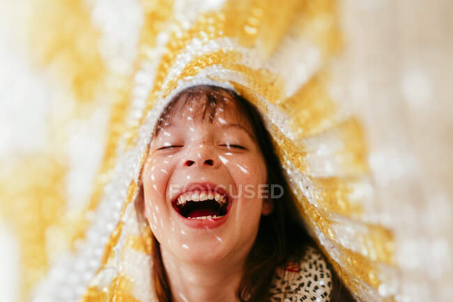 Ragazza ridente con lentiggini ricoperte di tessuto e raggi di sole sul viso — Foto stock