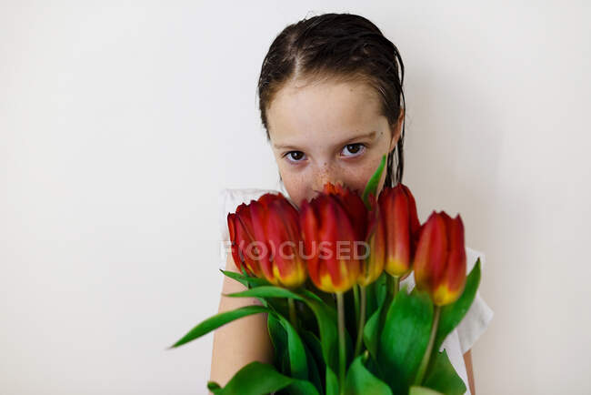 Süßes kleines Mädchen posiert mit roten Tulpen — Stockfoto