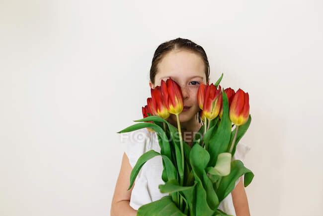 Carino bambina posa con tulipani rossi — Foto stock