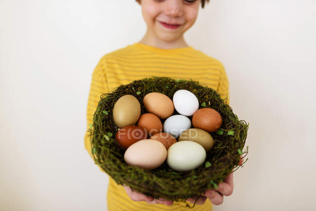Портрет усміхненого хлопчика, що тримає гніздо зі свіжими яйцями — стокове фото