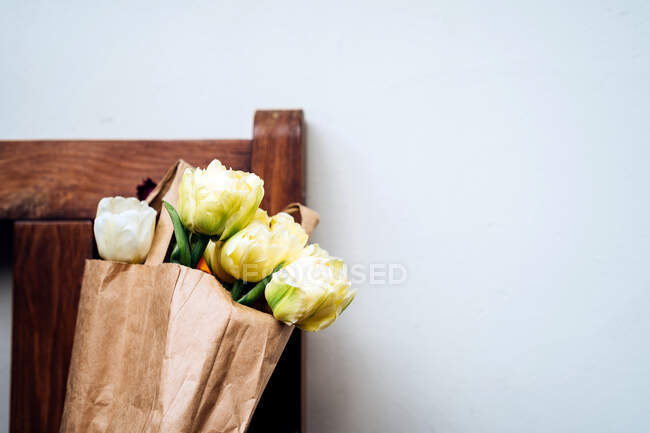 Тюльпаны в бумажном пакете на стуле — стоковое фото