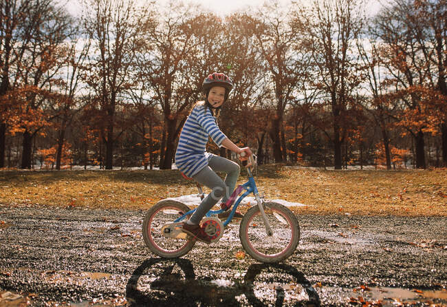 Chica sonriente montando una bicicleta en el parque, Estados Unidos - foto de stock