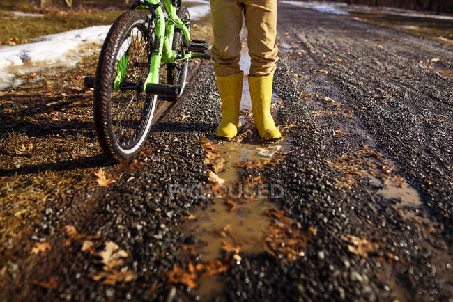 Nahaufnahme eines Jungen in Gummistiefeln, der neben seinem Fahrrad steht, Vereinigte Staaten — Stockfoto