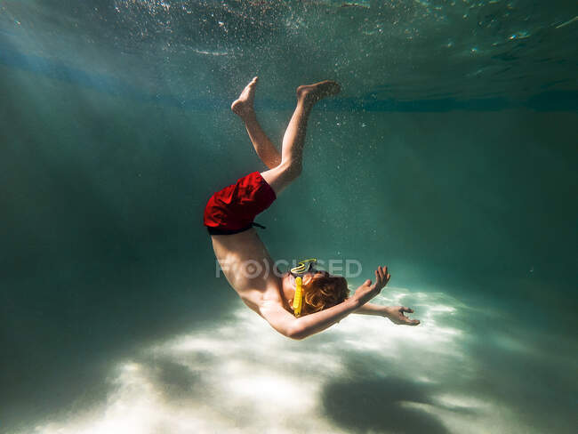 Menino nadando debaixo d 'água em uma piscina — Fotografia de Stock