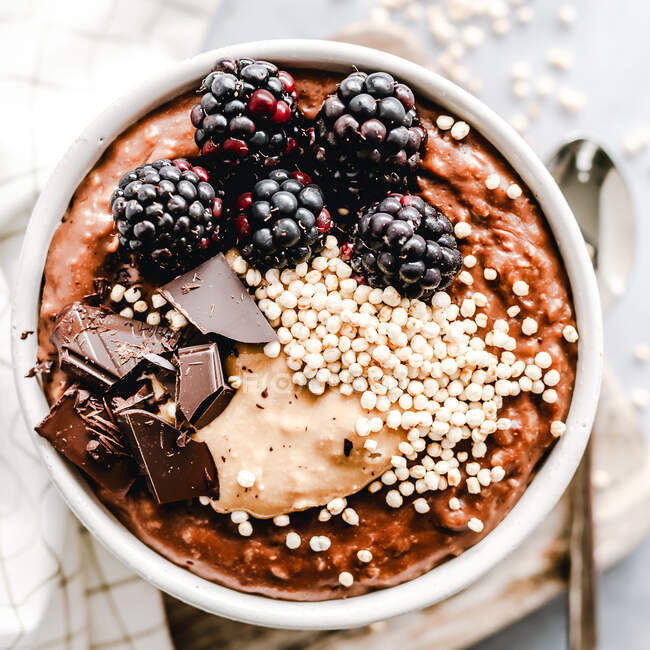 Vue aérienne de Farine d'avoine au chocolat avec beurre d'arachide, chocolat, mûres et quinoa soufflé — Photo de stock