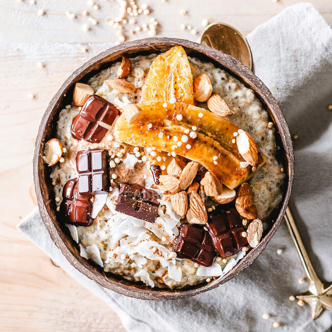 Oatmeal bowl topped with caramelized banana, almonds and chocolate — Stock Photo