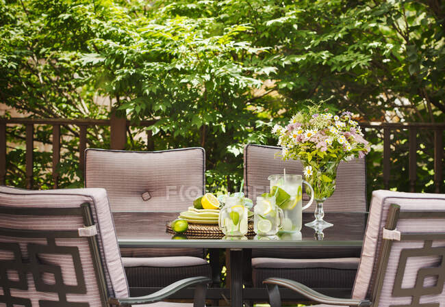 Лимонад в кувшине и чашки на столе в саду. — стоковое фото