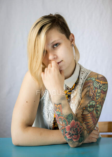 Ritratto di una donna con una manica tatuata seduta a un tavolo — Foto stock