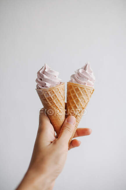 Mão de mulher segurando dois cones de waffle com chantilly — Fotografia de Stock