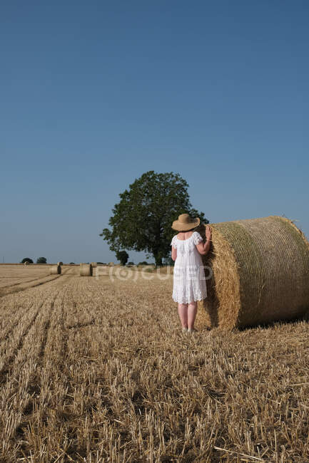 Femme debout près d'une balle de foin dans un champ, France — Photo de stock
