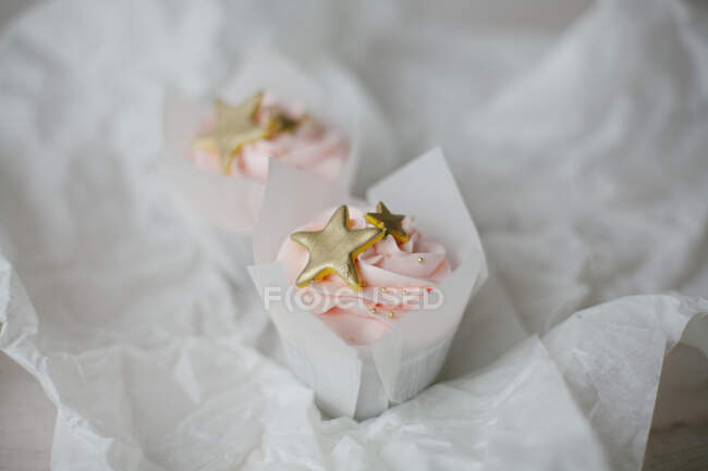 Two Cupcakes with gold colored decorations on parchment — Stock Photo