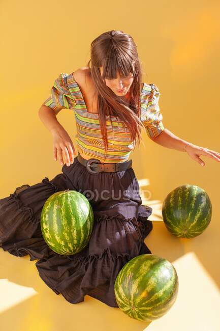 Smiling woman sitting on floor using watermelons as musical drums — Stock Photo