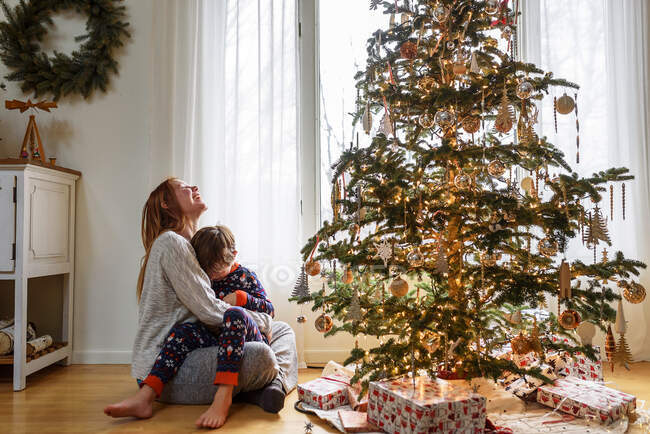 Mamma e figlio abbracciati dall'albero di Natale a casa — Foto stock