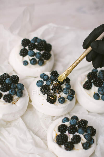 Женщина украшает Павловские десерты черникой и ежевикой — стоковое фото