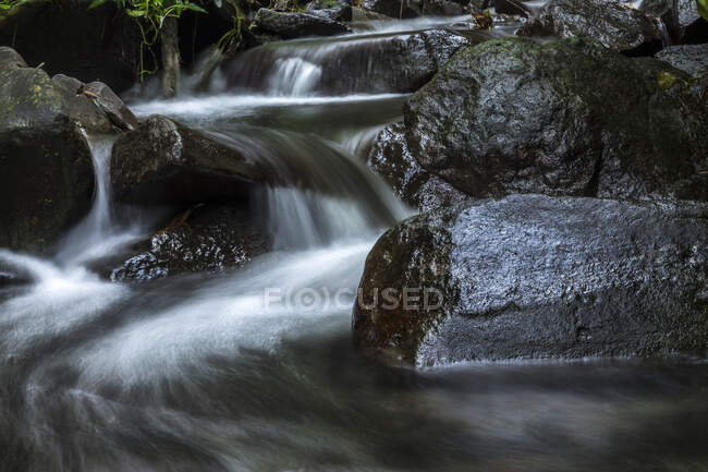 Lunga esposizione colpo di Close-up di acqua che scorre sopra le rocce, Indonesia — Foto stock