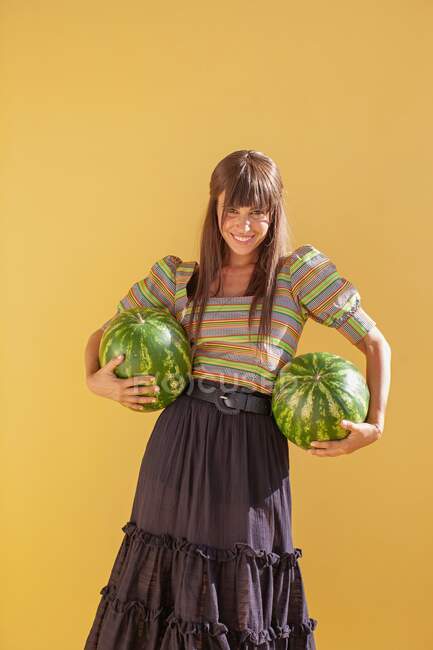 Smiling woman holding watermelons — Stock Photo