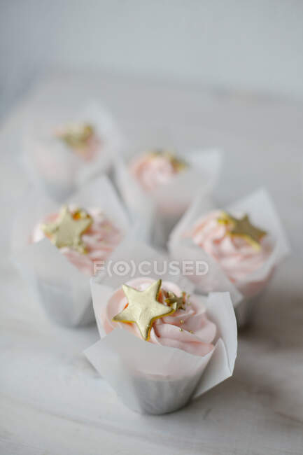 Cinq cupcakes avec glaçage et décoration dorée — Photo de stock