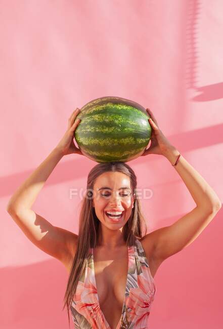 Lächelnde Frau mit einer Wassermelone über dem Kopf — Stockfoto