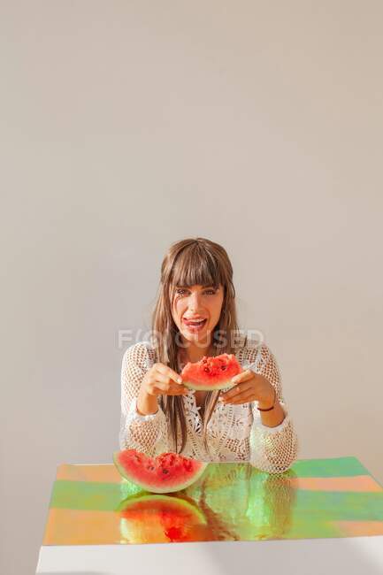 Женщина облизывает губы и держит в руках кусок арбуза — стоковое фото