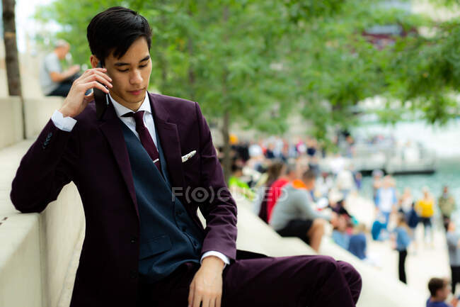 Joven Empresario sentado en Riverwalk hablando por teléfono, Chicago, Illinois, Estados Unidos - foto de stock