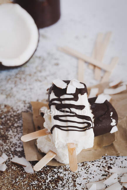 Tre yogurt al cocco e ghiaccioli al cioccolato su un tavolo — Foto stock