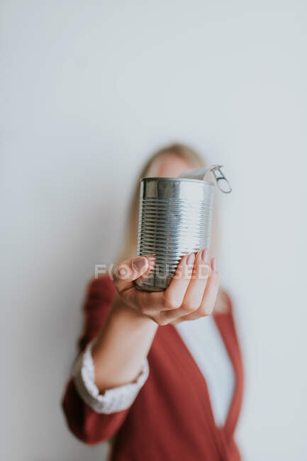 Mulher segurando lata de metal no fundo branco — Fotografia de Stock